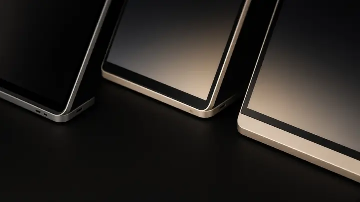 Three laptop corners on a black table. The screens cannot be read.